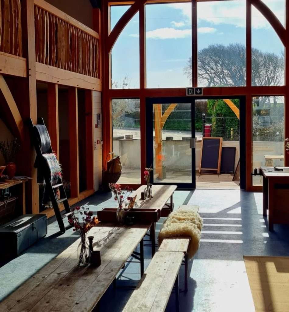 Sunlit seating area beside tall windows at Village Farm